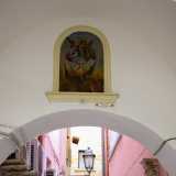 Arrivati sotto l�Arco del Vico ci basta alzare lo sguardo per trovarci davanti all�edicola dell�Arcangelo Michele, l�unica di Palo che rappresentano un santo, incastonata nel muro bianco. L�iconografia � quella tradizionale: Michele schiaccia con un piede il demonio mentre in una mano regge uno scudo con una grande croce